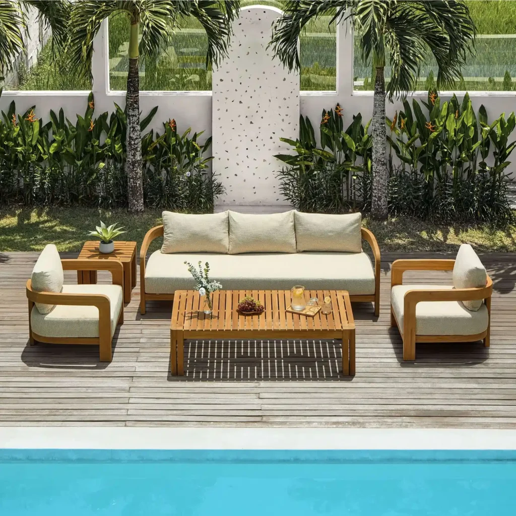 Cushioned wooden outdoor sofa, lounge chairs, and slatted coffee table beside a swimming pool